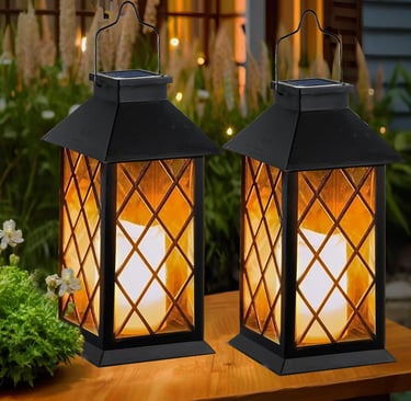 Two black decorative solar lanterns with flickering LED candles glowing on a garden table.
