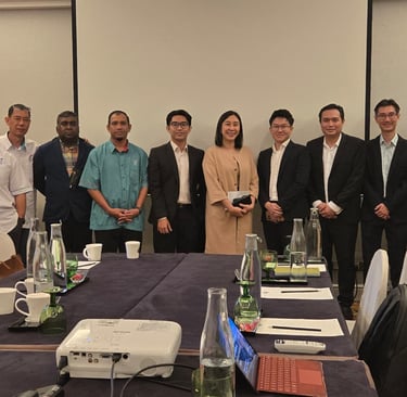 Professional group posing for a corporate business meeting in a conference room with a projector.