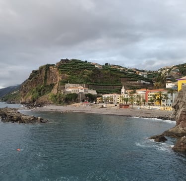 Scenic coastal view of Ponta do Sol village in Madeira with rocky cliffs and pebble beach.