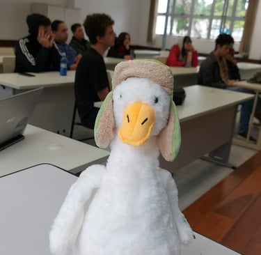 Ganso de pelúcio em primeiro plano, atrás tem membros da equipe sentados em reunião