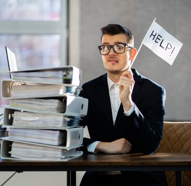 a man in a suit and glasses sitting at a desk with a laptop computer