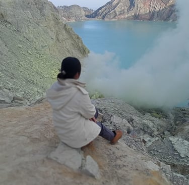 a woman sitting on a rock in the mountains