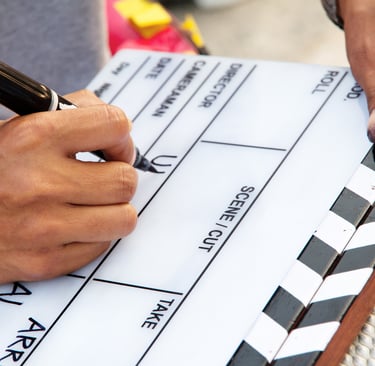 a person holding a pen and writing on a clapperboard