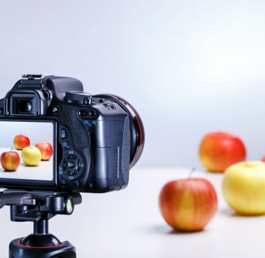 Appareil photo photographiant des pommes sur une table blanche