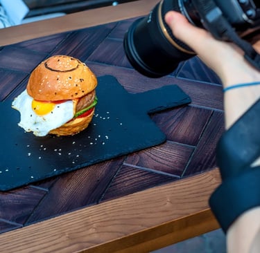 Un photographe prend une photo d'un burger sur une ardoise