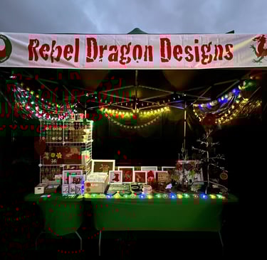 The Rebel Dragon Designs stall lit up with christmas and fairy lights at a Christmas market