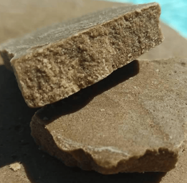 Hachís de CBD natural prensado sobre fondo marrón claro