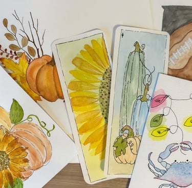 A collection of watercolor paintings laying stacked haphazardly.