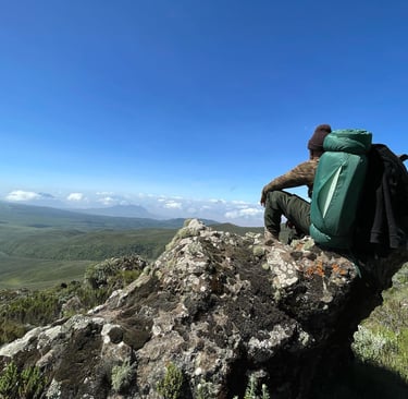 a man sitting on a rock with a backpack on top of it