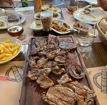 a table with a large wooden cutting board with steak and fries