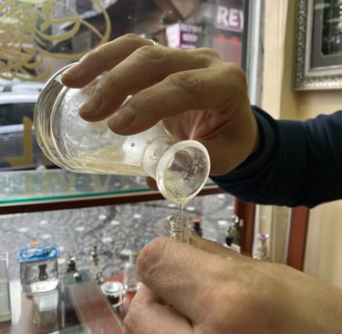 a person is holding a glass of oil based perfume
