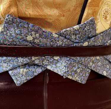 The blue floral belt of a gold brocade and brown satin evening gown