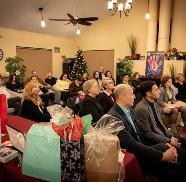 a group of people sitting in a room with christmas presents