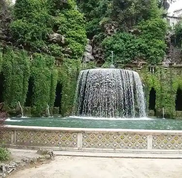 Cascade se jetant dans 1 bassin et entourée de plantes tombantes et de colonnes