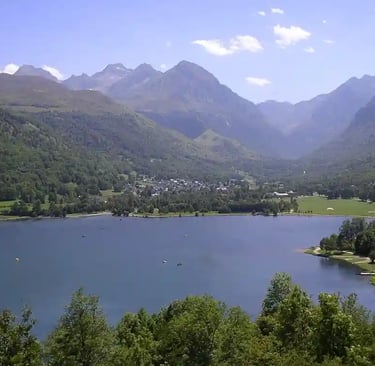 Lac bordé de bois en premier plan et village de Genos en arrière plan au pied des montagnes