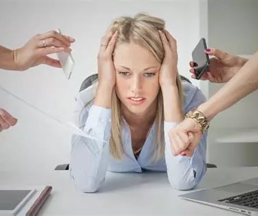 Femme blonde de face stressée se tient la tête à 2 mains et penchée en avant