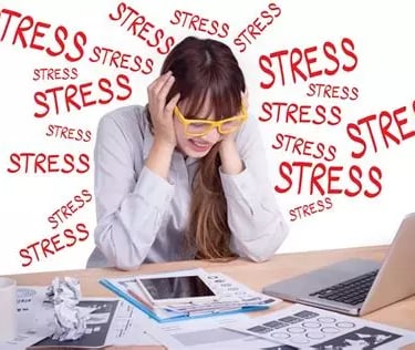 Femme stressée penchée en avant avec lunettes jaunes, se tient la tête mains sur les oreilles