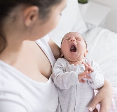 A tired mom holding her yawning toddler at bedtime. Learn how pediatric chiropractic in Franklin, TN