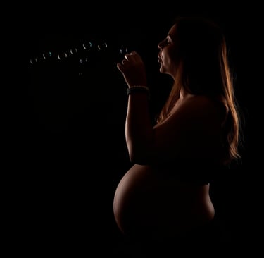 a pregnant woman blowing bubbles in the dark