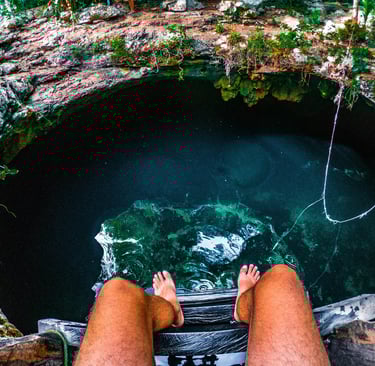 a person sitting on the edge of a Cenotes in Mexico