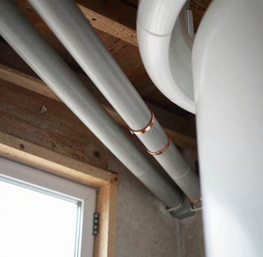 Grey Poly B water pipes with copper crimp fittings running along a basement ceiling in Langley home