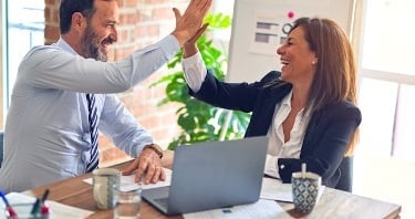 Two cybersecurity professionals celebrating passing their certification exam.
