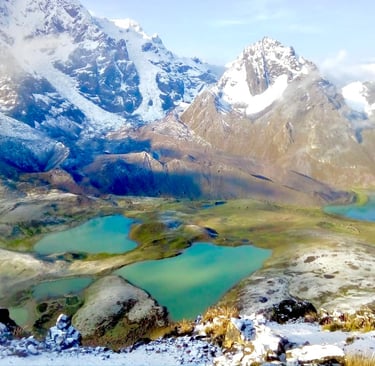 Panoramic view of turquoise glacial lakes nestled among snow-capped mountain peaks in the Andes.