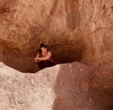A woman hiker sits in an Arizona red rock desert cave formation during a canyon trek.
