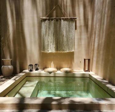 Luxury private plunge pool with boho macrame wall hanging and stone seating in a sun-drenched courtyard.