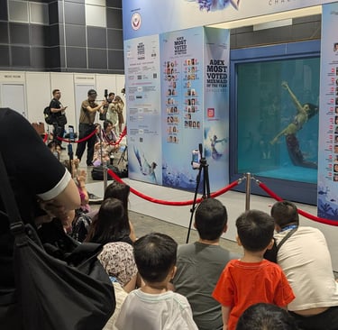 an audience watching an underwater performnce in a dive tank showing mermaids