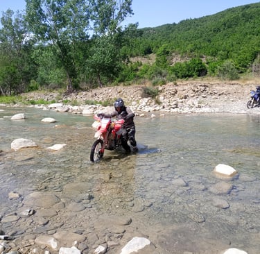 a person riding a motorcycle through a river
