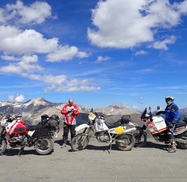 a group of motorcyclists standing in front of a mountain
