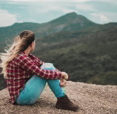 a woman sitting on a rock with her hair in a ponytail