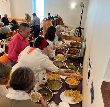 a group of people standing around a table with food