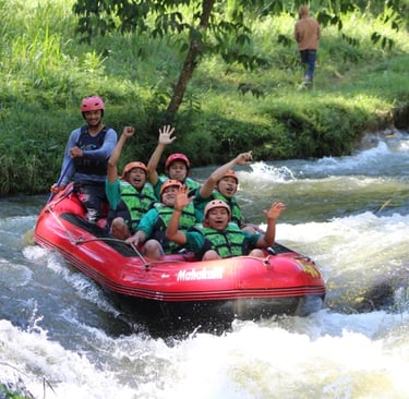 Peserta menikmati keseruan Pangalengan rafting di Sungai Palayangan dengan perahu karet merah bersama Fluir Adventure.