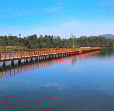 Jembatan gantung oranye di atas danau Situ Cileunca yang biru jernih dengan latar belakang hutan pinus dan langit biru cerah