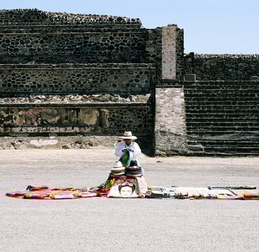 a man in a hat selling hats on a blanket