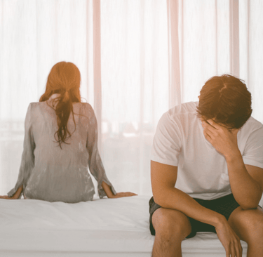 a man and woman sitting on a bed stressfully