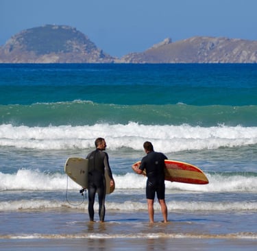 two surfers standing in the surf at the beach