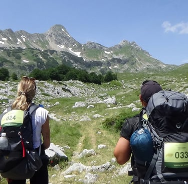 two people walking up a hill with backpacks