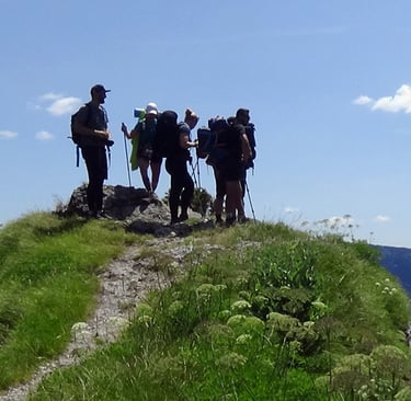six trekkers standing at the top of a distant hill