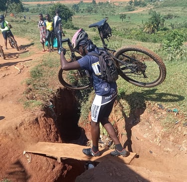 a man carrying a bicycle on a dirt road