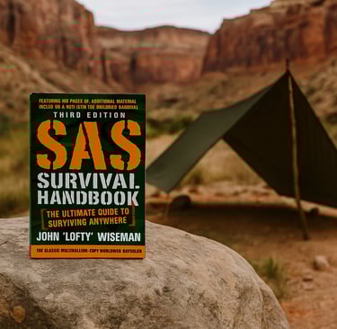 SAS Survival Handbook by John "Lofty" Wiseman with tarp shelter in desert canyon