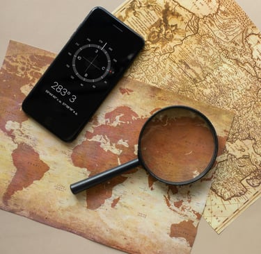 Smartphone and magnifying glass over survival maps, showing digital and analog navigation