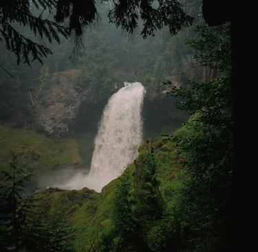 Tall waterfall surrounded by lush forest and cliffs, highlighting natural navigation and water sourcing in the wild