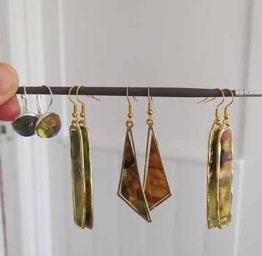 a person holding a pair of earrings with a picture of a woman's hand
