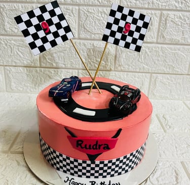 Customized race car themed birthday cake with checkered flags and toy cars for a 9th birthday party.