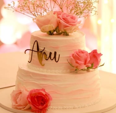 Elegant two-tier white and pink ombré cake decorated with fresh roses and a custom script topper.