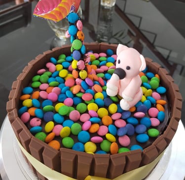 Chocolate Kit Kat cake decorated with colorful chocolate candies and a pink fondant bear topper.