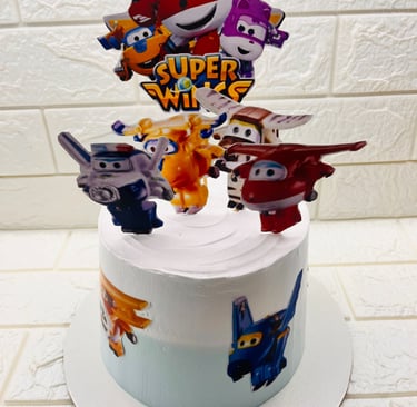 A Super Wings themed birthday cake with white frosting and airplane character cake toppers.